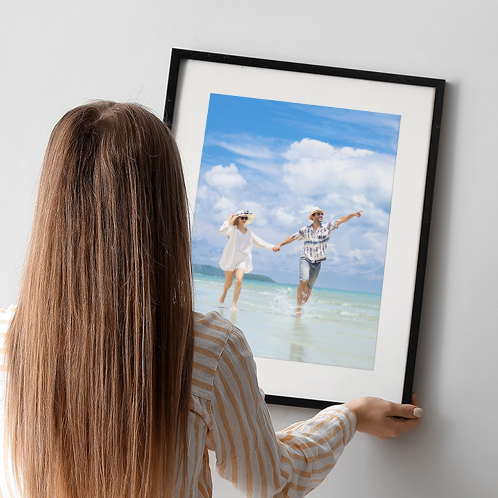 Lady putting up oak framed print of a family on a wall